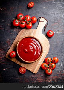 Tomato sauce on a wooden cutting board. Against a dark background. High quality photo. Tomato sauce on a wooden cutting board.