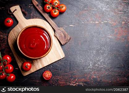 Tomato sauce on a wooden cutting board. Against a dark background. High quality photo. Tomato sauce on a wooden cutting board.