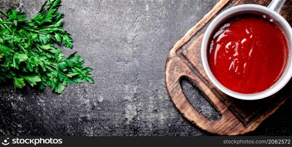Tomato sauce on a wooden cutting board. On a black background. High quality photo. Tomato sauce on a wooden cutting board.