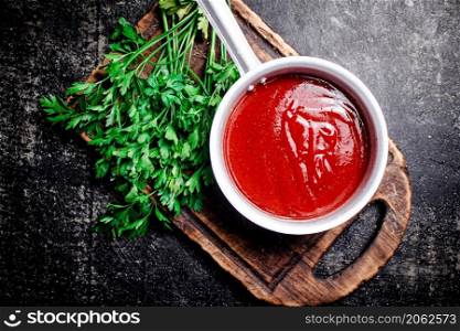Tomato sauce on a wooden cutting board. On a black background. High quality photo. Tomato sauce on a wooden cutting board.