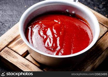 Tomato sauce on a wooden tray. On a black background. High quality photo. Tomato sauce on a wooden tray.