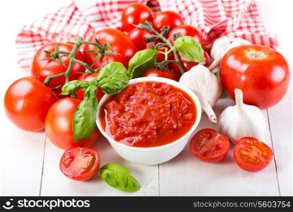 tomato sauce with fresh vegetables on wooden table
