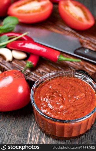 tomato sauce with garlic and basil in the pan on a wooden table. tomato sauce with garlic and basil