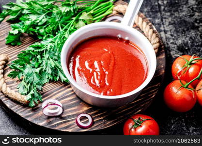 Tomato sauce with parsley and onion rings on the tray. On a black background. High quality photo. Tomato sauce with parsley and onion rings on the tray.