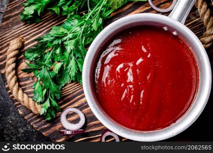 Tomato sauce with parsley and onion rings on the tray. On a black background. High quality photo. Tomato sauce with parsley and onion rings on the tray.