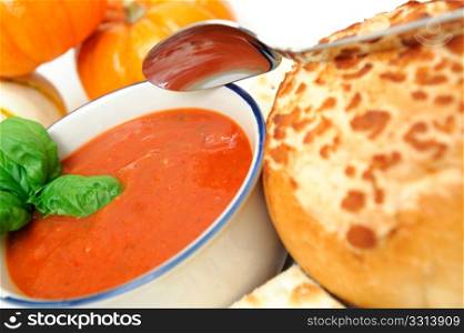 Tomato Soup And Basil. Hot tomato soup on an autumn day topped with fresh basil leaves and a French bread roll on the side
