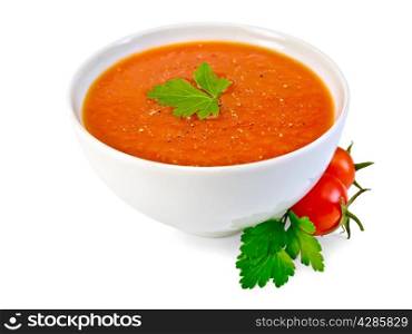 Tomato soup in a white bowl, parsley, tomatoes isolated on white background