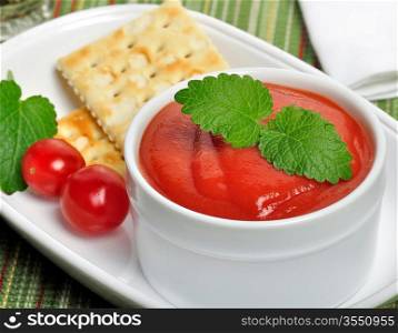 Tomato Soup In A White Bowl With Cracker And Spices