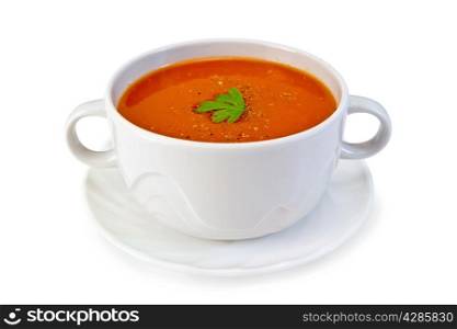 Tomato soup in a white bowl with parsley on a plate isolated on white background