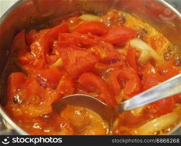tomato soup preparation. tomato soup preparation boiling in a sauce pan on gas cooker with spoon