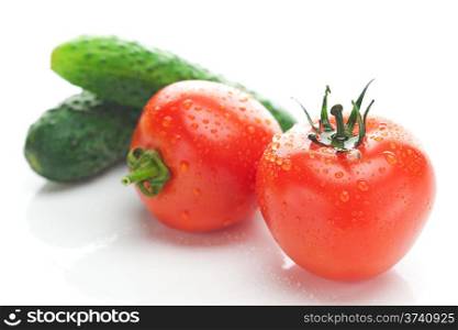 tomato with water drops and cucumbers isolated on white