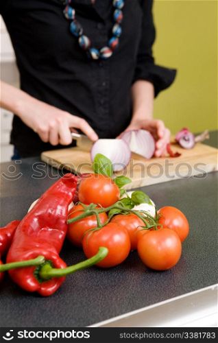 Tomatoes and a Chillie pepper sitting on the couter waiting to be sliced. - Shallow depth of field with ocus is on the vegetables in the foreground of the images.