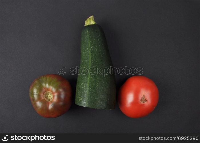 Tomatoes and zucchini on black background