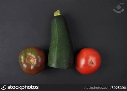 Tomatoes and zucchini on black background