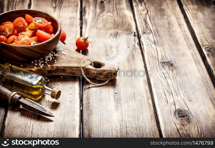 Tomatoes background. Fresh tomatoes in a wooden bowl with olive oil. On wooden background.. Fresh tomatoes in a wooden bowl with olive oil.