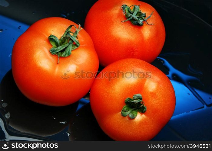 Tomatoes close up over blue background with water