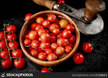 Tomatoes for marinating in a wooden plate. On a black background. High quality photo. Tomatoes for marinating in a wooden plate.