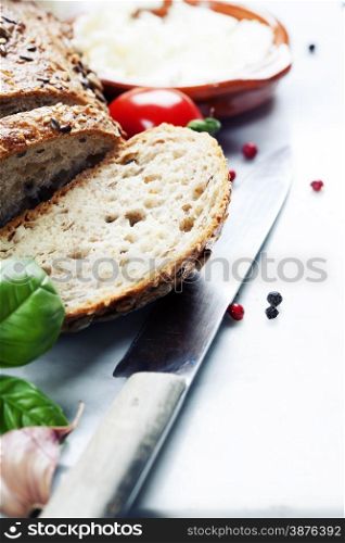 Tomatoes, fresh bread, cheese and basil on white marble background