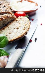 Tomatoes, fresh bread, cheese and basil on white marble background