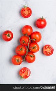 Tomatoes, fresh red ripe on branch, whole and cut in half, on rustic table top view.