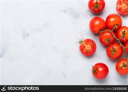 Tomatoes, fresh red ripe on branch, whole and cut in half, on rustic table top view with copy space.