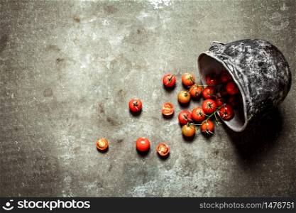 Tomatoes in the old pot. Wet stone background. . Tomatoes in the old pot.