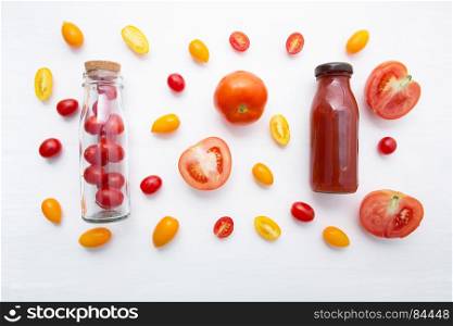Tomatoes juice in bottle and fresh tomatoes on white wooden background.