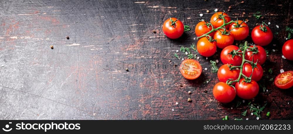 Tomatoes on a branch with pieces of greens and spices. Against a dark background. High quality photo. Tomatoes on a branch with pieces of greens and spices.