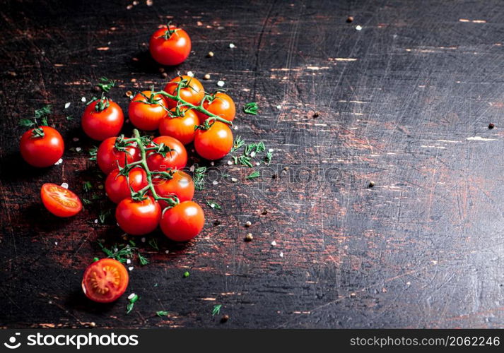 Tomatoes on a branch with pieces of greens and spices. Against a dark background. High quality photo. Tomatoes on a branch with pieces of greens and spices.