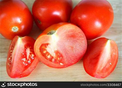 Tomatoes, one of them cut-up, on a chopping board