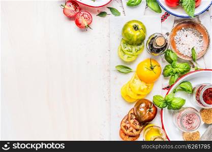 Tomatoes salad preparation. Tomatoes cooking ingredients on white marble cutting board. Various Colorful sliced tomatoes on white wooden background, top view, place for text, border