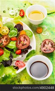 Tomatoes salad with olive oil and balsamic vinegar on green background, top view, close up
