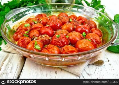 Tomatoes small baked with spice and salt in a glass pan on a wooden boards background