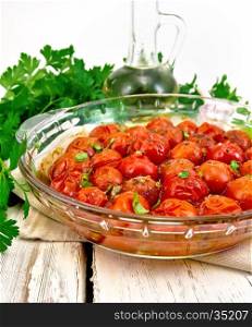 Tomatoes small baked with spices, garlic and salt in a glass pan on a wooden boards background