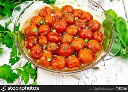 Tomatoes small baked with spices, garlic and salt, parsley in a glass pan on a wooden boards background