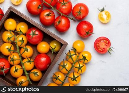 Tomatoes variety on rustic table in wooden box red yellow whole and cut, top view