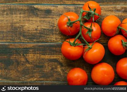 Tomatoes with branch on a wooden rustic background