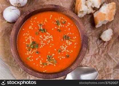 tomatos soup puree in wooden bowl on crushed brown paper