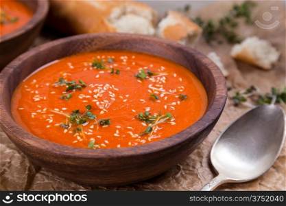 tomatos soup puree in wooden bowl on crushed brown paper