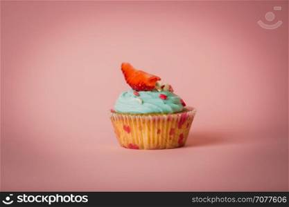 Toned closeup photo of cupcake with buttercream decorated with sprinkles and fresh strawberry