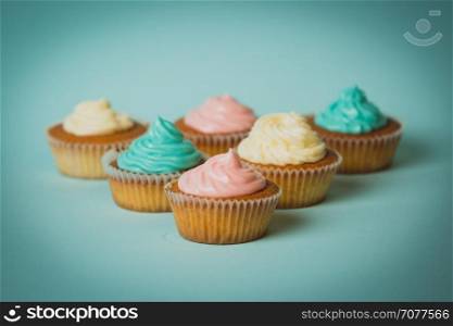 Toned closeup photo of freshly baked colorful cupcakes on blue background