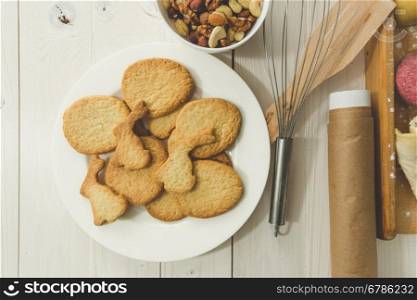 Toned closeup photo of freshly baked cooking next to kitchen utensils on white wooden background