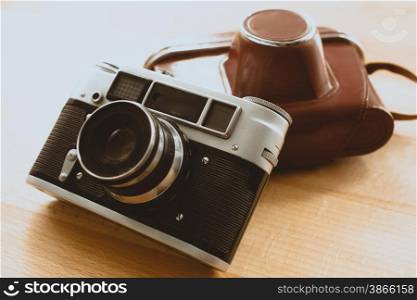 Toned closeup photo of retro camera with brown leather case