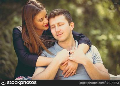 Toned closeup portrait of beautiful woman hugging boyfriend at park