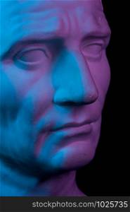 Toned gypsum copy of ancient statue of Guy Julius Caesar Octavian Augustus head for artists on a black background. Plaster sculpture of man face. Blue and pink toned.. Gypsum copy of ancient statue Augustus head isolated on black background. Plaster sculpture man face.