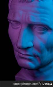 Toned gypsum copy of ancient statue of Guy Julius Caesar Octavian Augustus head for artists on a black background. Plaster sculpture of man face. Blue and pink toned.. Gypsum copy of ancient statue Augustus head isolated on black background. Plaster sculpture man face.