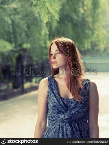 Toned image of a red haired women relaxing in a park.