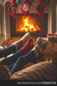 Toned image of couple wearing woolen socks relaxing at burning fireplace