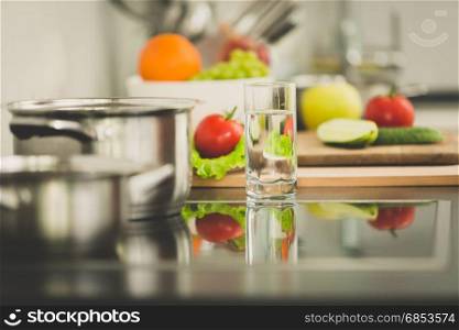 Toned image of fresh vegetables lying next to electric stove on modern kitchen