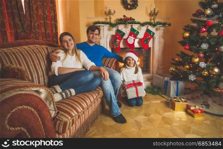 Toned image of happy family with daughter sitting on sofa at living room